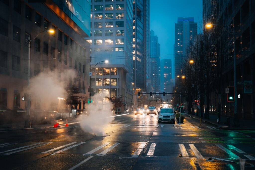 A rainy night in downtown Seattle with city lights and steam creating a moody urban atmosphere.